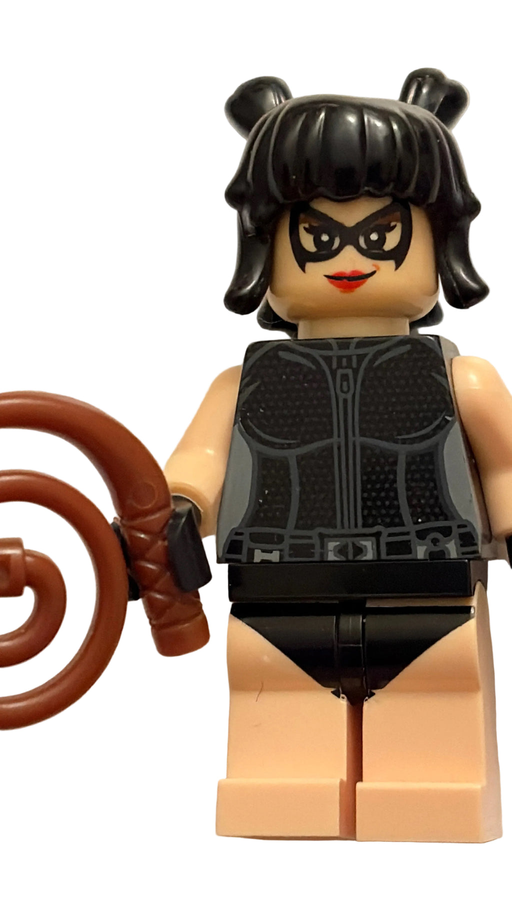 A custom-built female LEGO minifigure with black hair in two buns, a black mask, a black vest, and a brown curly tail accessory, standing against a plain off-white background.