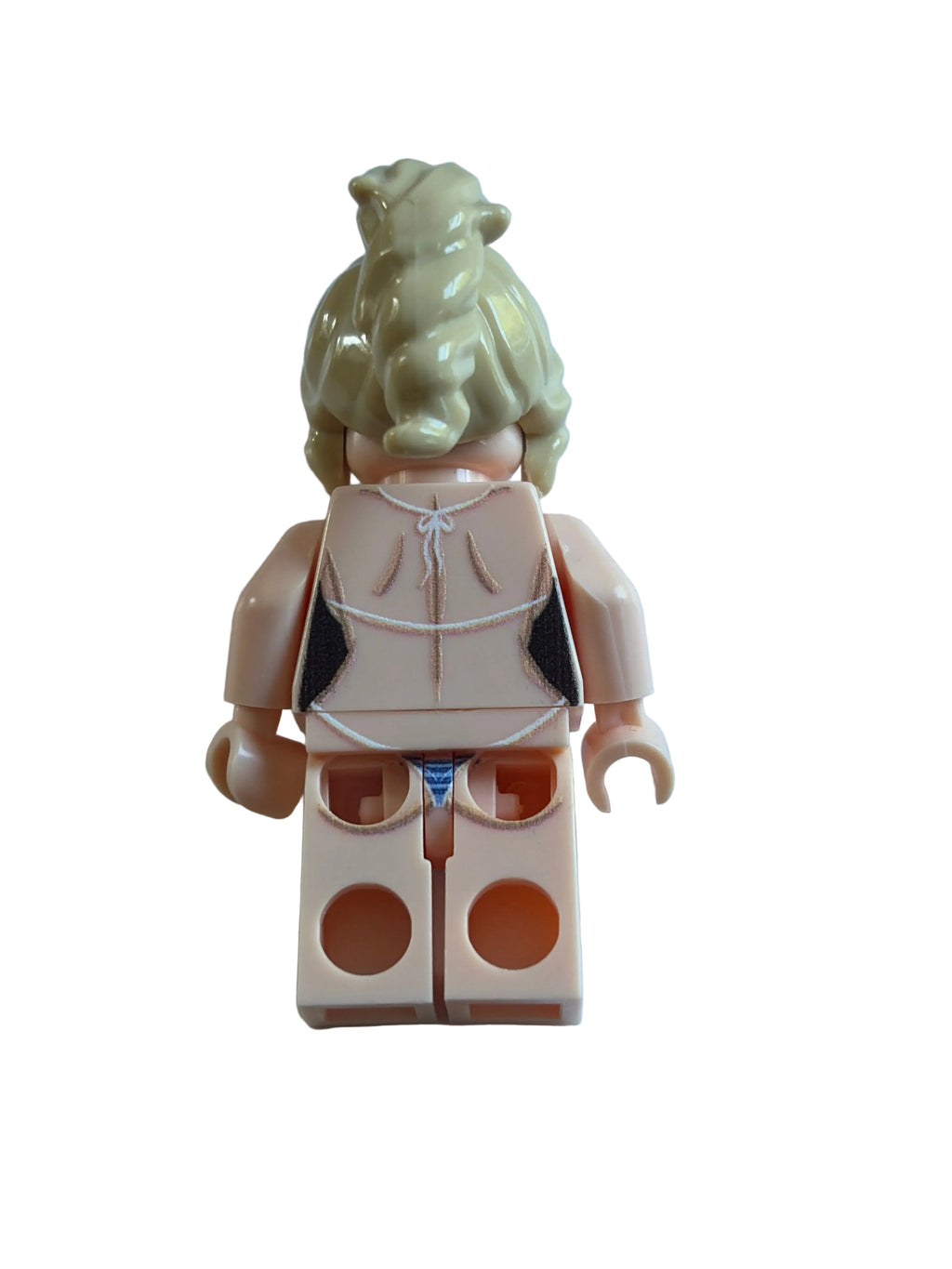 A toy minifigure torso with a blonde head and beige plastic body, wearing a black and white bikini top and blue bottoms, lying on a light blue surface.