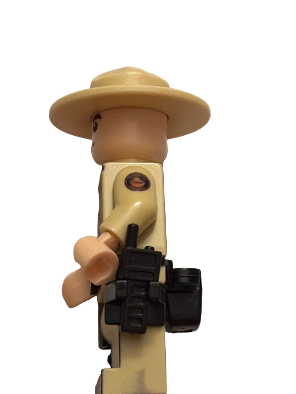 A close-up of a toy soldier's torso and hat, featuring a beige plastic body, a tan wide-brimmed hat, and a black rifle accessory, set against a plain off-white background.