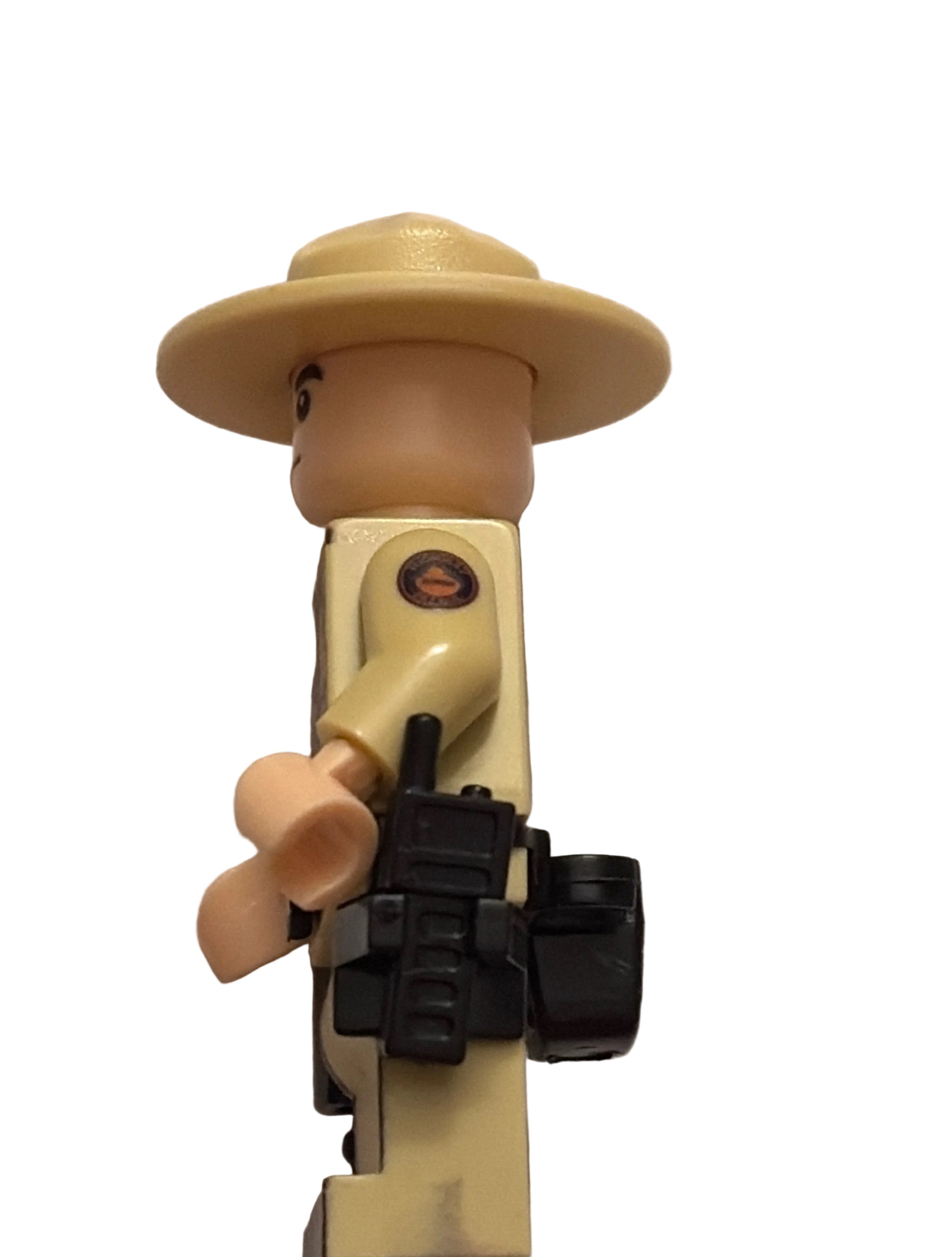 A close-up of a toy soldier's torso and hat, featuring a beige plastic body, a tan wide-brimmed hat, and a black rifle accessory, set against a plain off-white background.