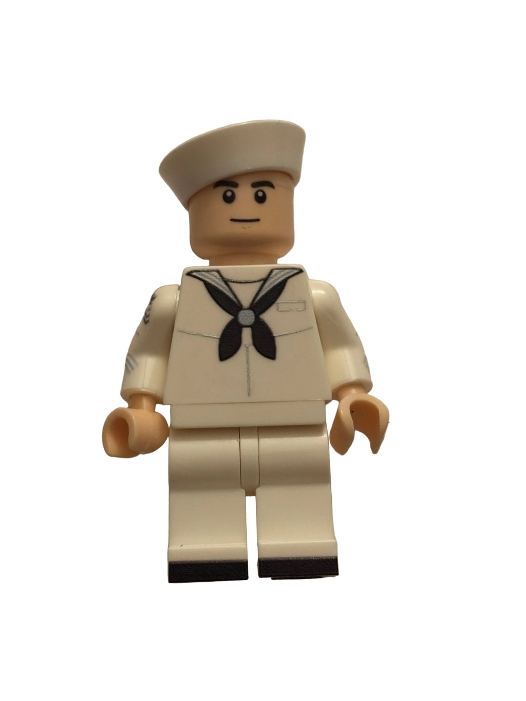 A small toy minifigure with a beige head and hands, wearing an off-white uniform with a black leaf emblem on the chest, photographed against a plain light background.