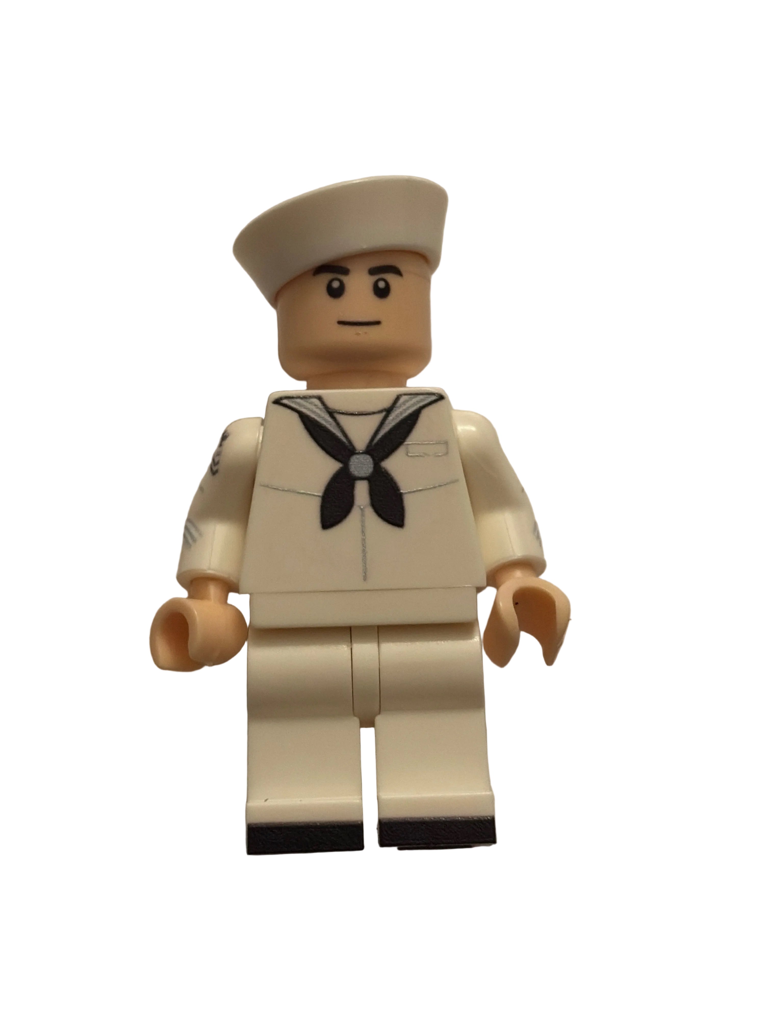 A small toy minifigure with a beige head and hands, wearing an off-white uniform with a black leaf emblem on the chest, photographed against a plain light background.