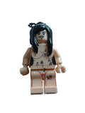 A custom-built minifigure resembling a tattooed man with long black hair, standing next to a beige plastic block or box on a light blue background.