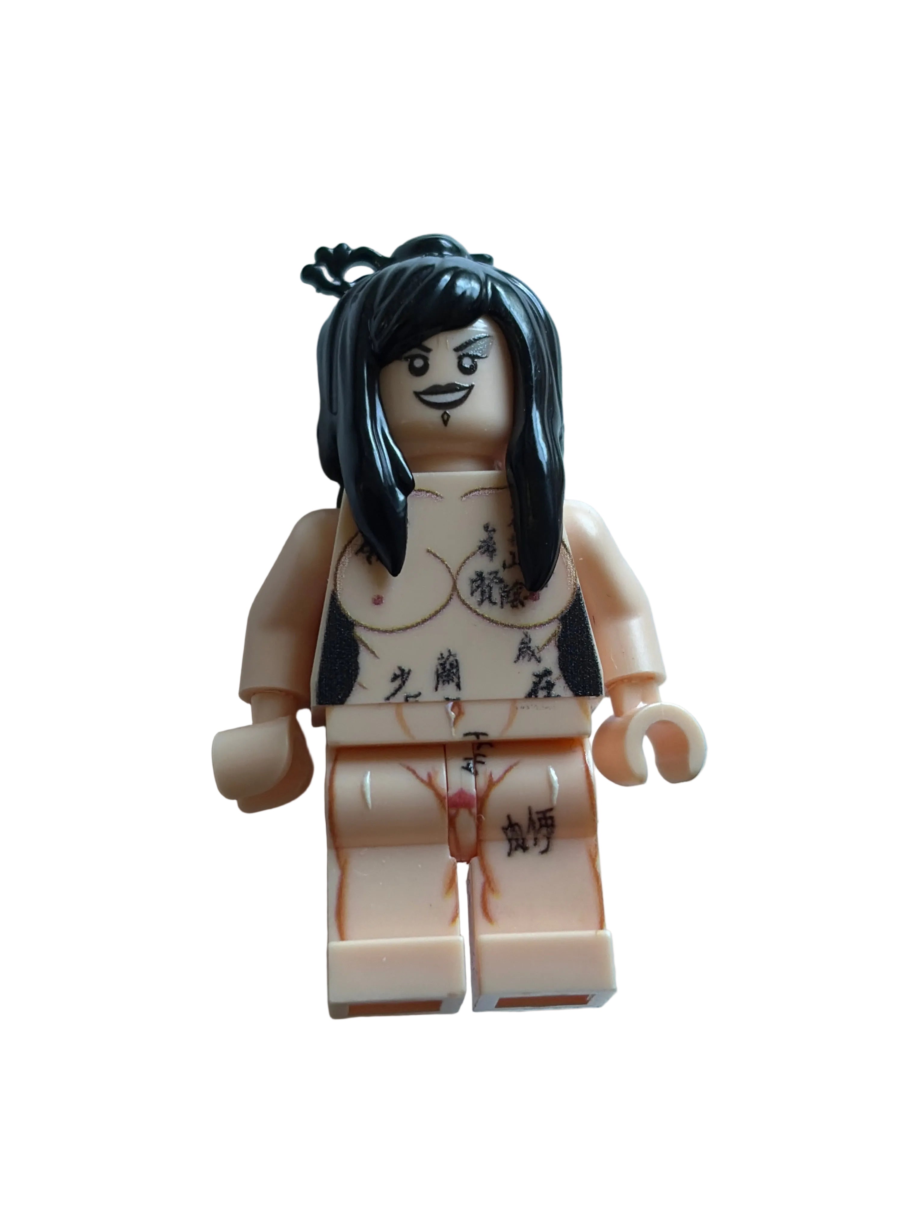 A custom-built minifigure resembling a tattooed man with long black hair, standing next to a beige plastic block or box on a light blue background.