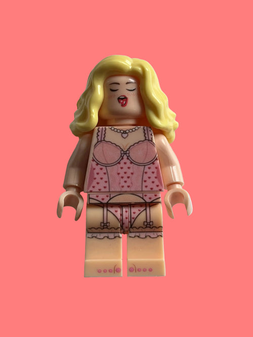 A custom LEGO minifigure with blonde hair, wearing a pink polka-dot lingerie set, photographed against a plain light gray background.