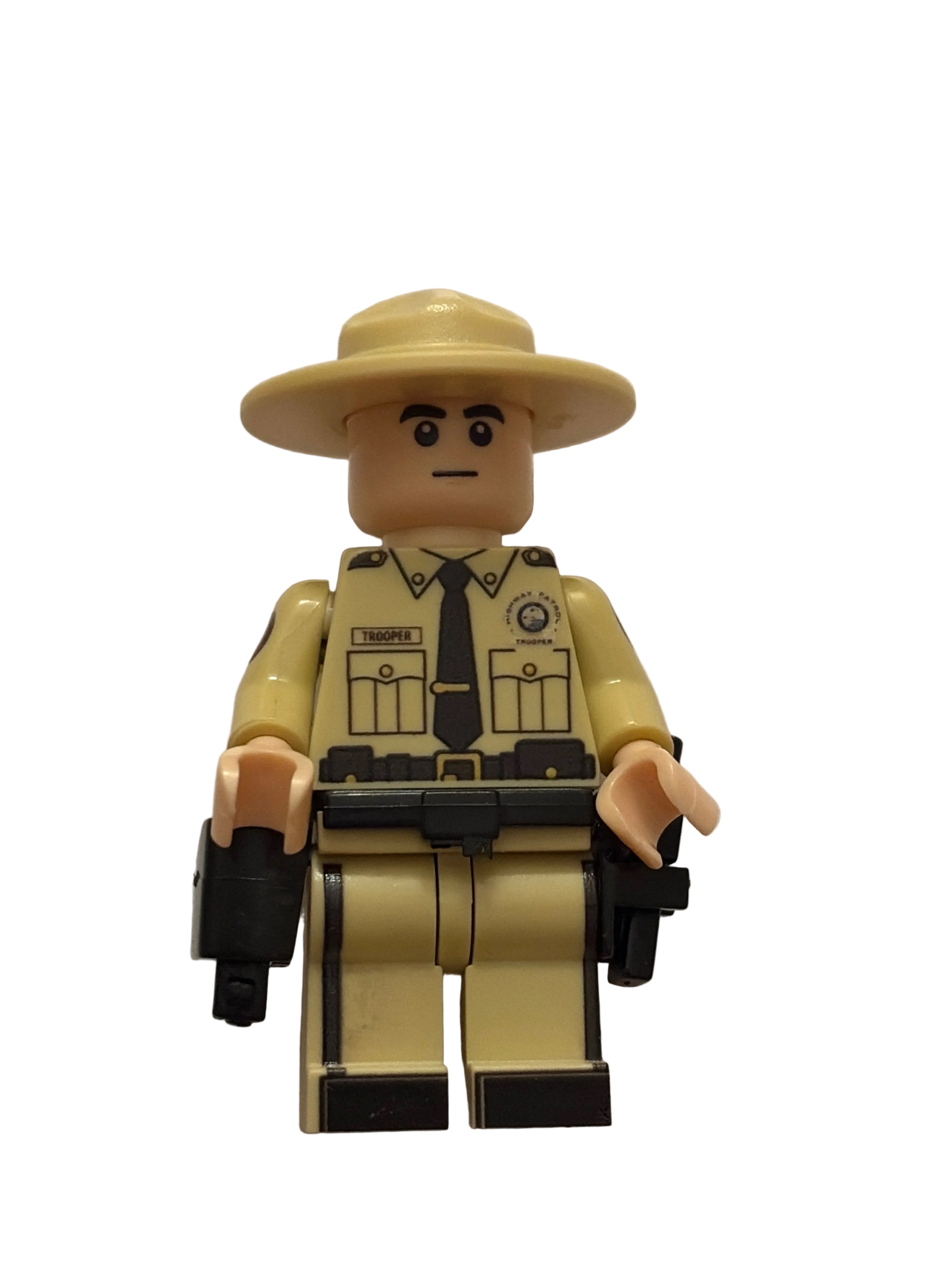 A toy minifigure with a beige hat and tan body, printed with a police uniform and holding black accessories, photographed against a plain off-white background.