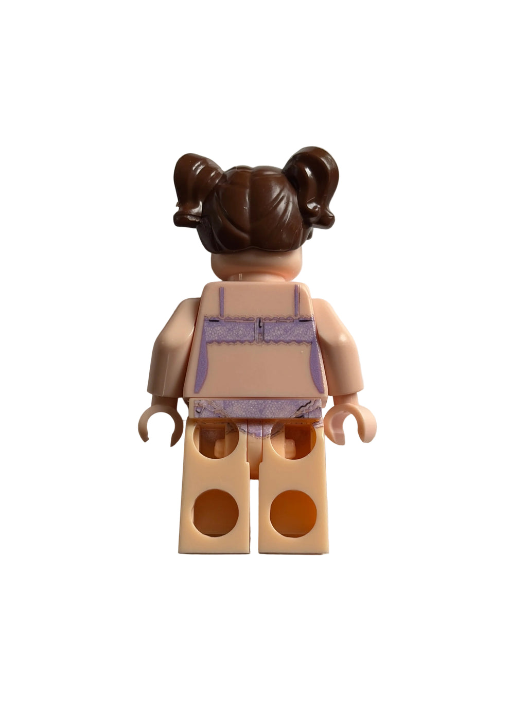 A small toy minifigure torso with a brown hair bun, peach skin-tone arms and legs, and a lavender-and-white top, photographed on a plain light background.