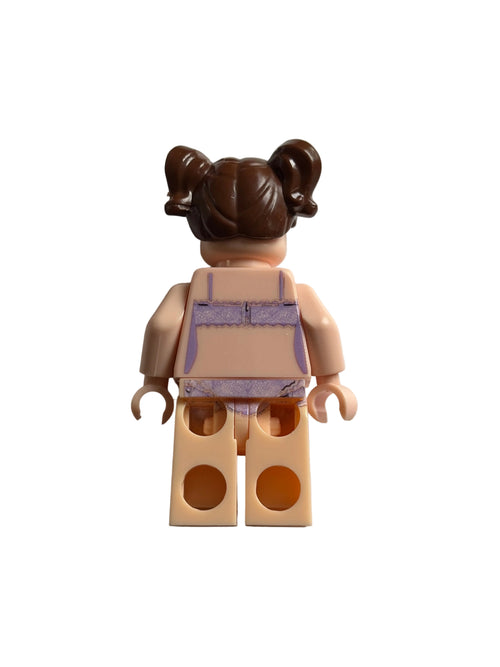 A small toy minifigure torso with a brown hair bun, peach skin-tone arms and legs, and a lavender-and-white top, photographed on a plain light background.