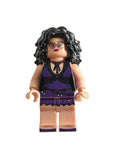 A small toy minifigure with curly black hair, glasses, and a purple-and-black outfit, photographed on a plain light background.
