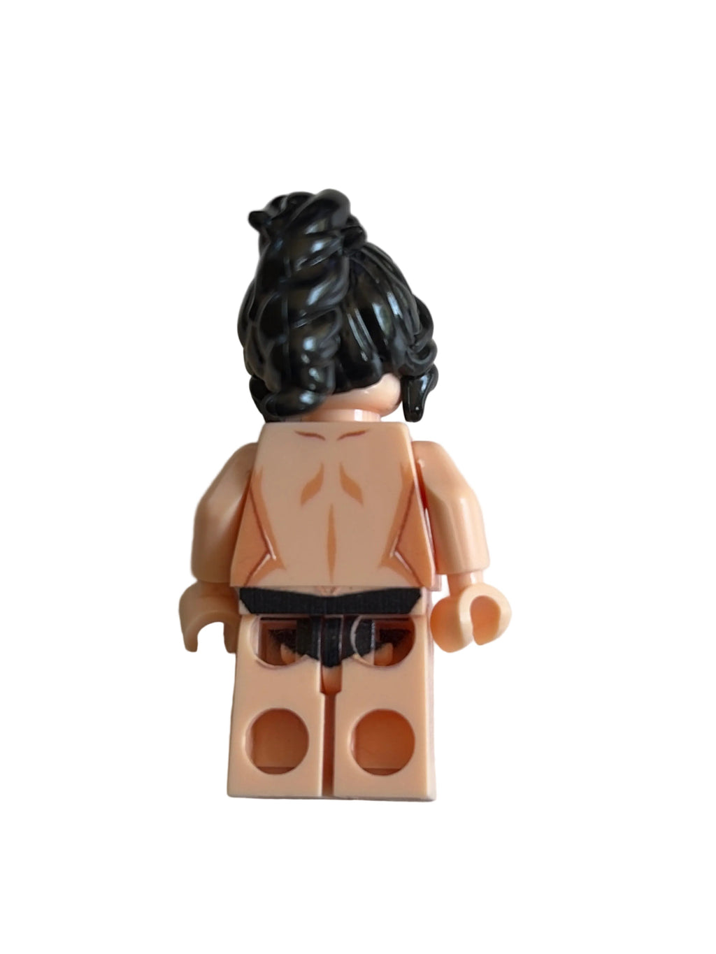 A back view of a toy minifigure with black hair, a tan skin tone, and a black waistband, isolated on a white background.