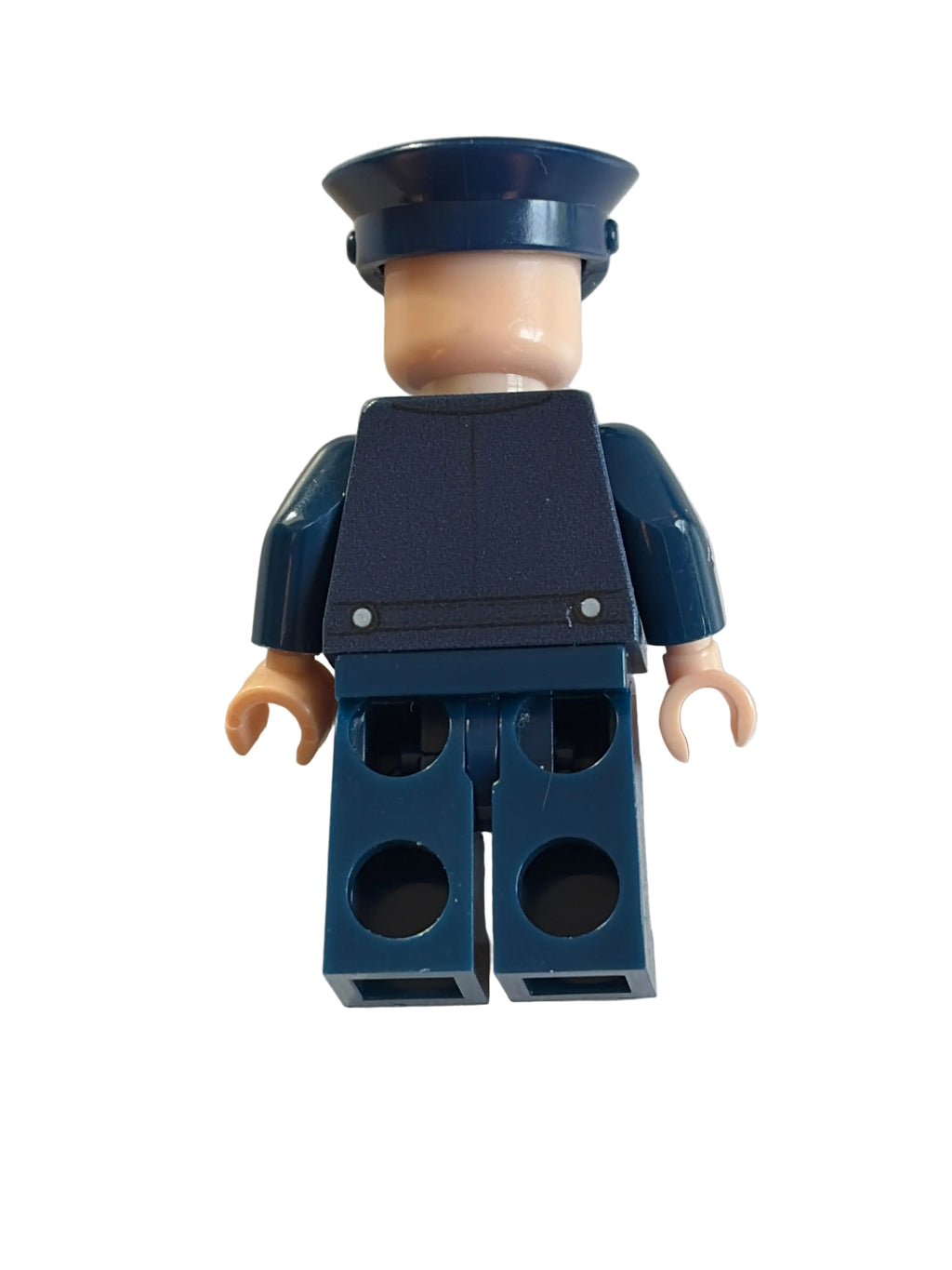 A toy minifigure torso with dark blue arms and torso, beige neck and hands, and a dark blue hat, photographed on a plain off-white surface.