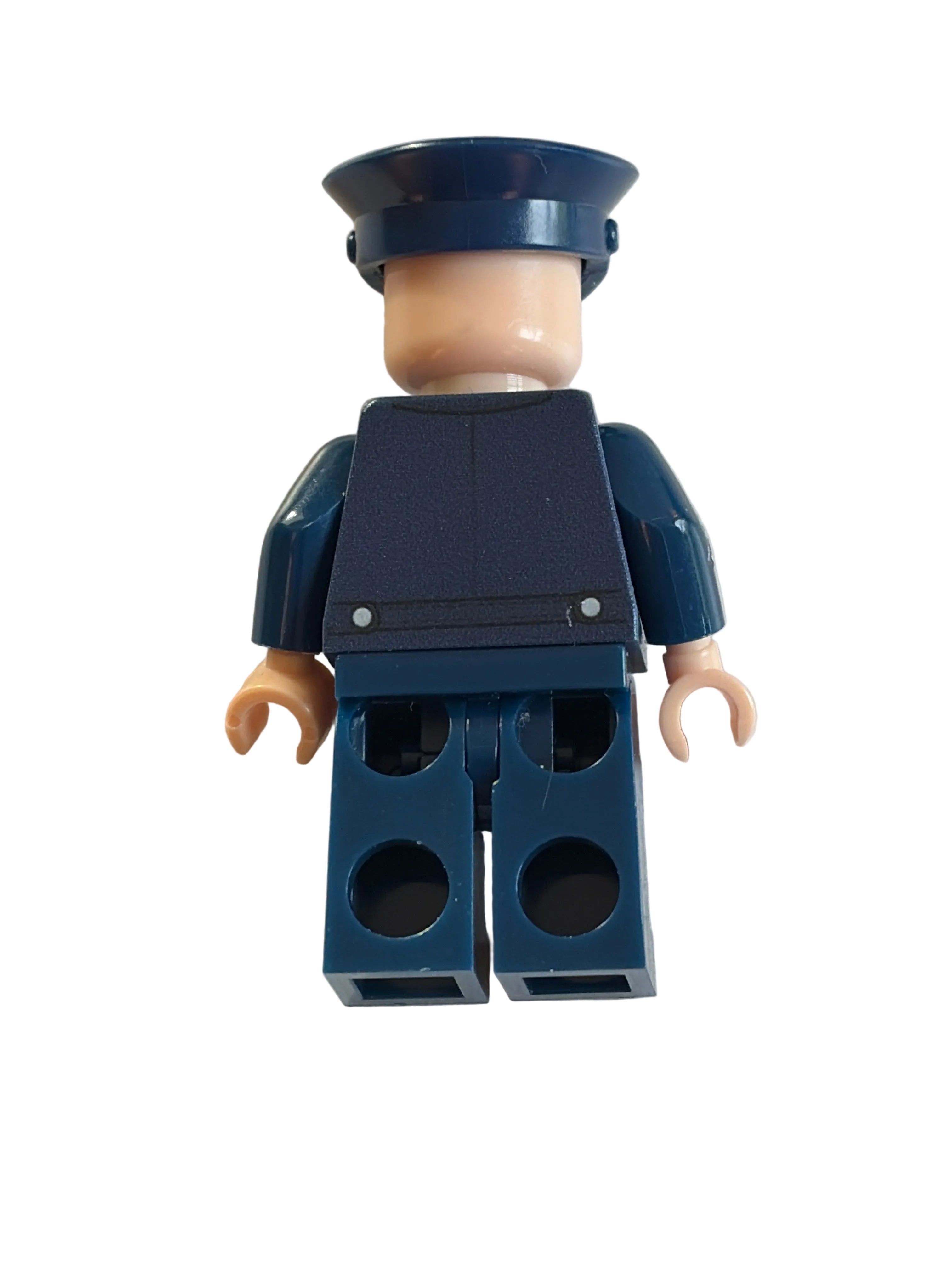 A toy minifigure torso with dark blue arms and torso, beige neck and hands, and a dark blue hat, photographed on a plain off-white surface.
