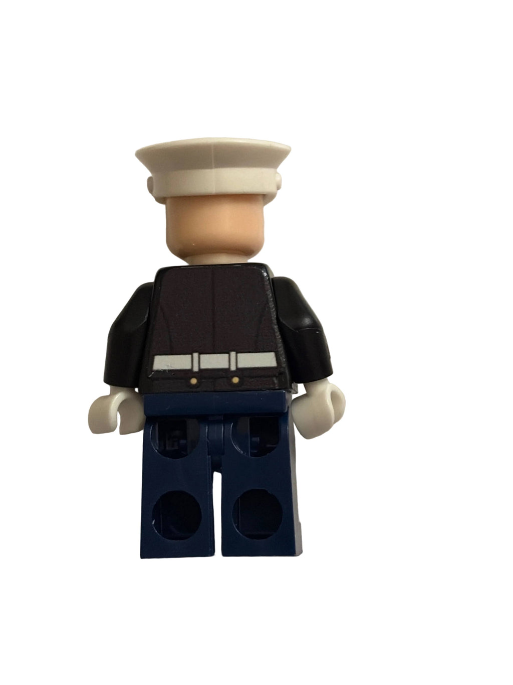 A toy minifigure shown from the back, wearing a cream-colored cap, a black top with a light gray belt detail, and dark blue pants, isolated on a white background.