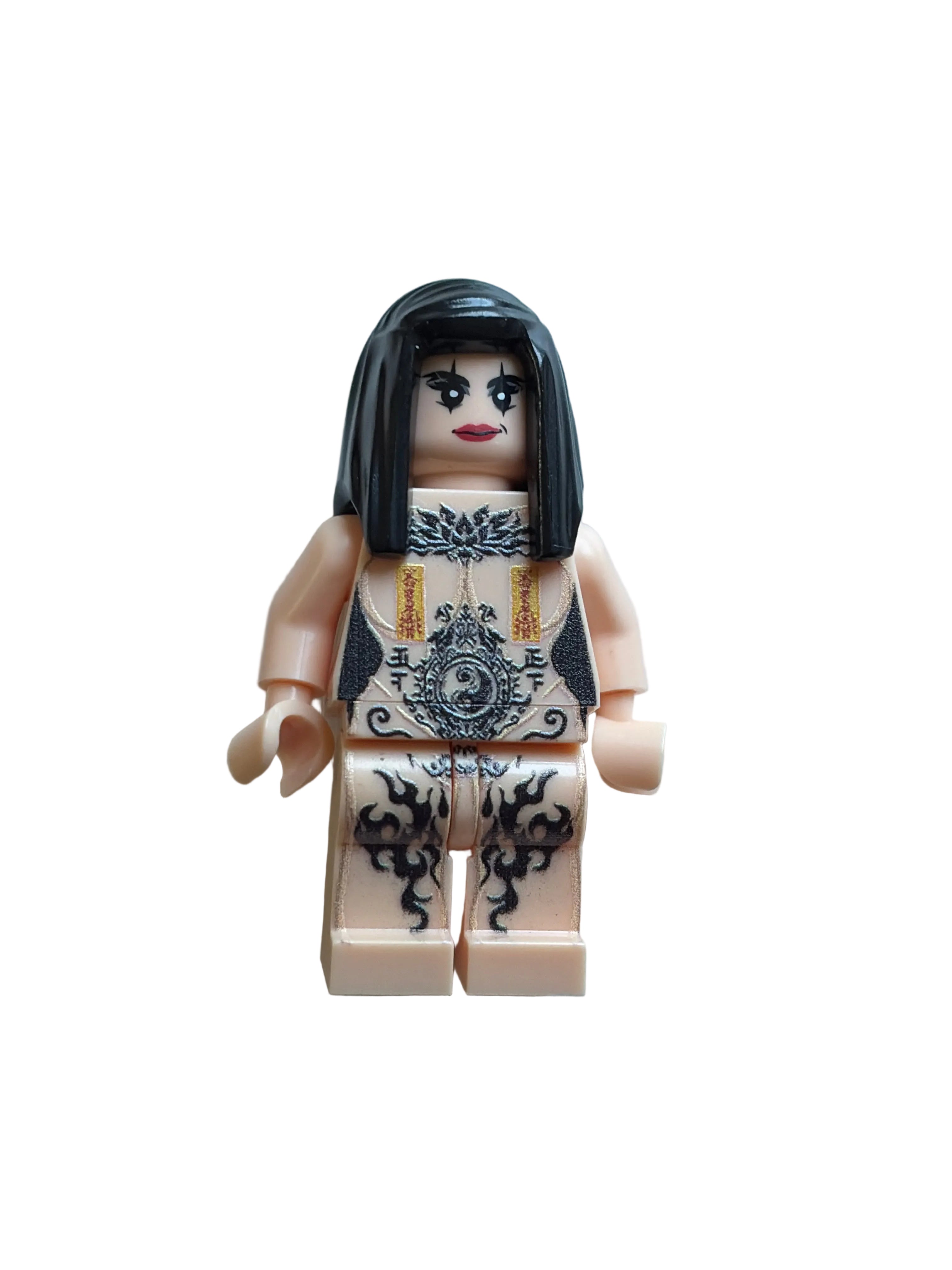 A custom-built toy minifigure resembling a gothic woman, constructed from beige plastic bricks with black hair, printed black and white gothic patterns on the torso, and red lips, photographed on a light blue background.