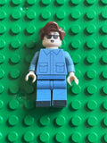 A custom LEGO minifigure with brown hair, sunglasses, and a blue jumpsuit, standing on a green LEGO baseplate.