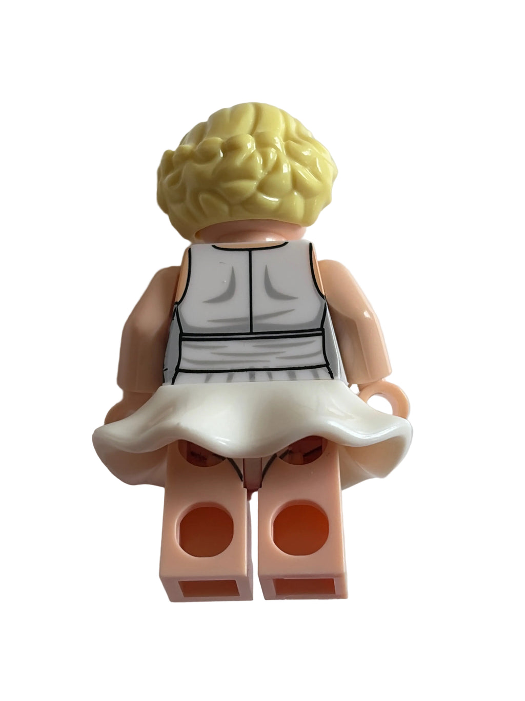 A small toy minifigure torso with a yellow hair piece, peach skin-tone arms and legs, a white dress, and a printed white-and-black torso, photographed on a plain light background.