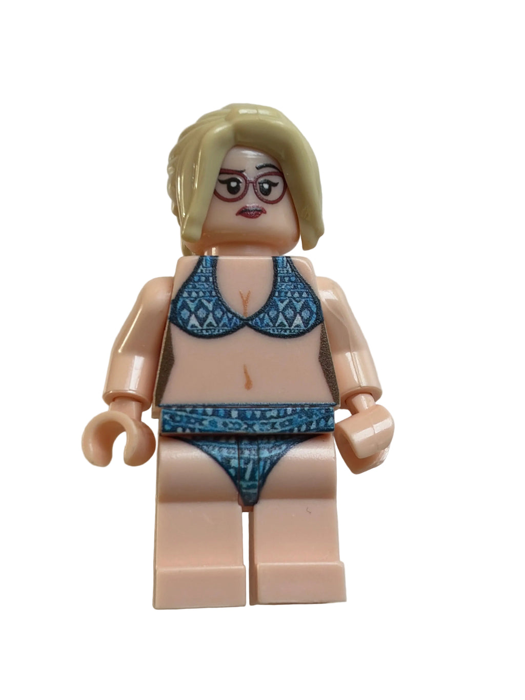 A custom-built toy minifigure with blonde hair, glasses, and a blue patterned bikini, positioned on a plain off-white background.