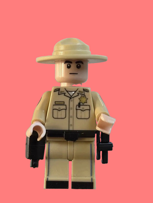 A toy minifigure dressed as a sheriff or ranger, wearing a beige wide-brim hat, matching beige uniform with black detailing, and holding black pistols, isolated on a white background.