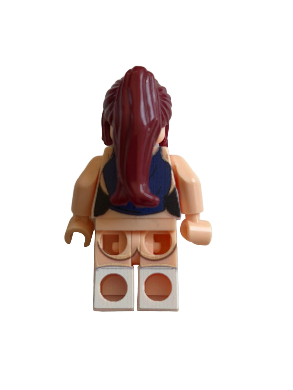 A single toy minifigure torso with beige skin-tone arms and hands, a blue top, and dark reddish-brown hair, photographed on a plain off-white background.
