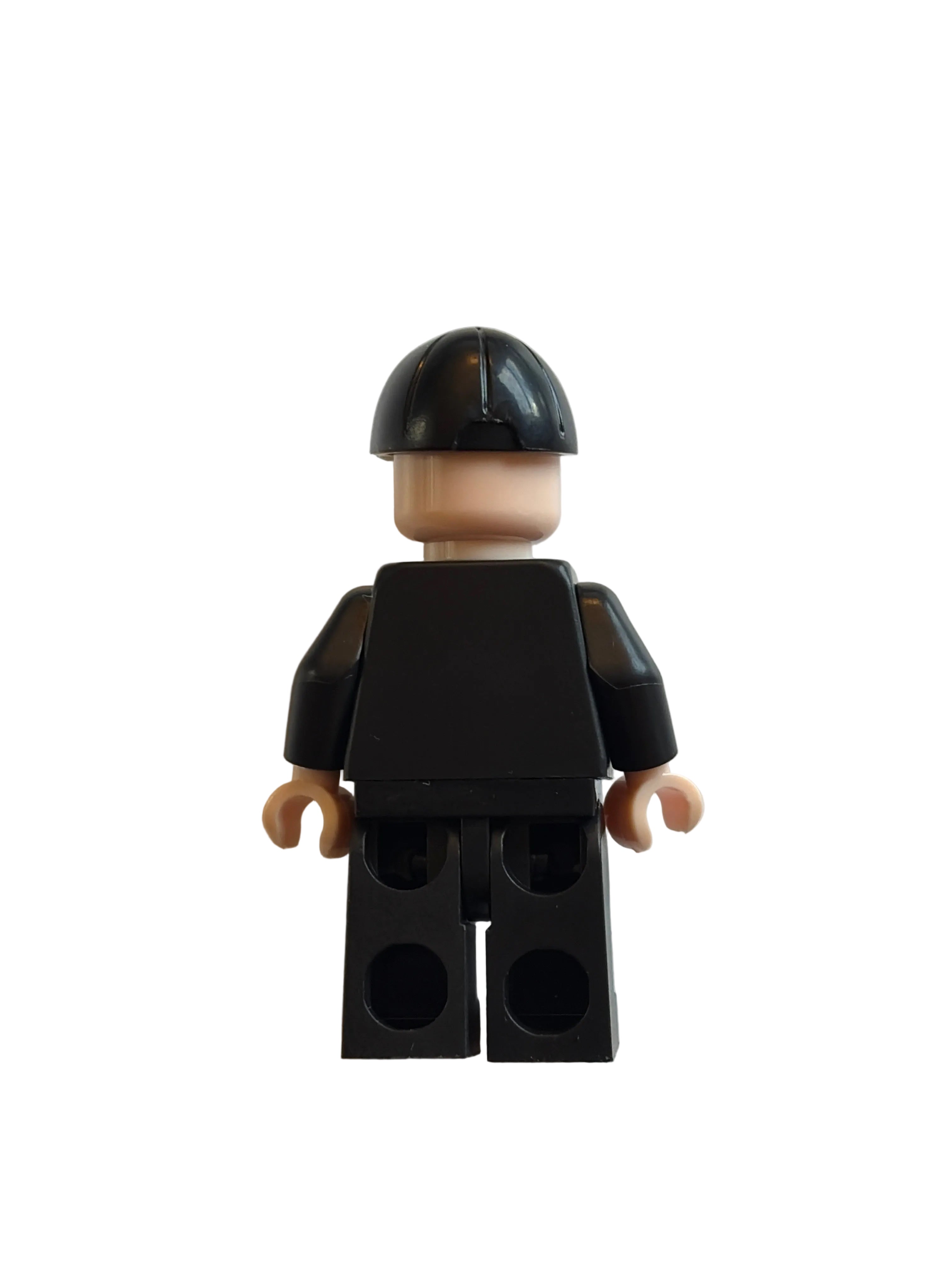 A small black toy minifigure torso with beige hands and a black-and-beige helmet, photographed on a plain off-white background.