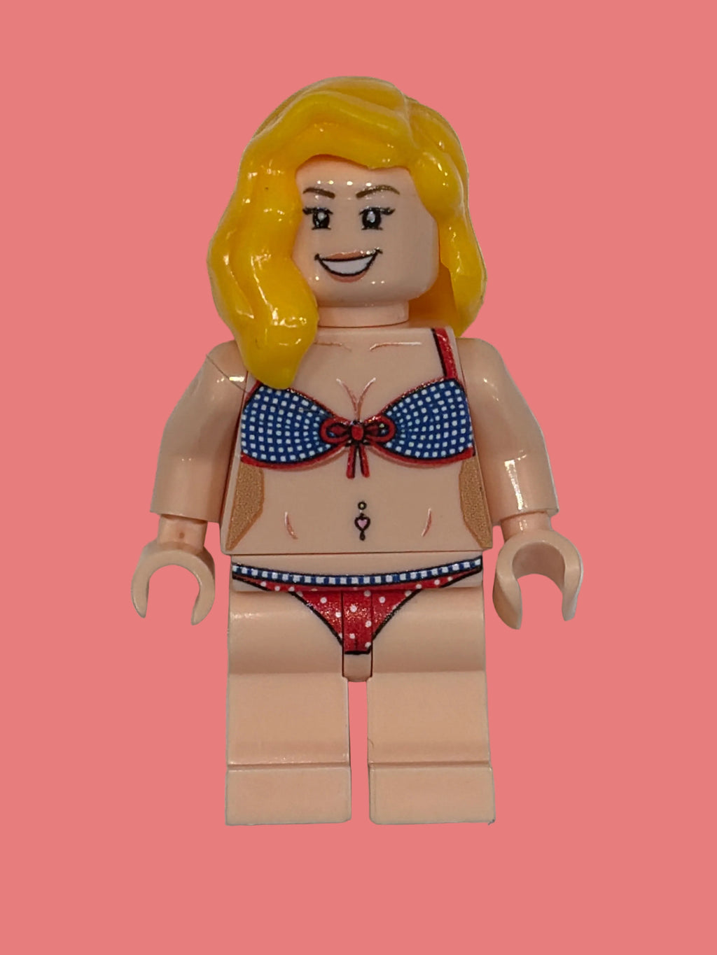 Ellie Lego style custom Minifigure in a red white and blue polka dot bikini with blonde hair smiling face on a pink background