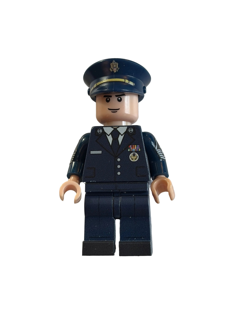 A small toy minifigure dressed in a dark navy blue police or military uniform with a matching peaked cap, photographed on a plain off-white surface.