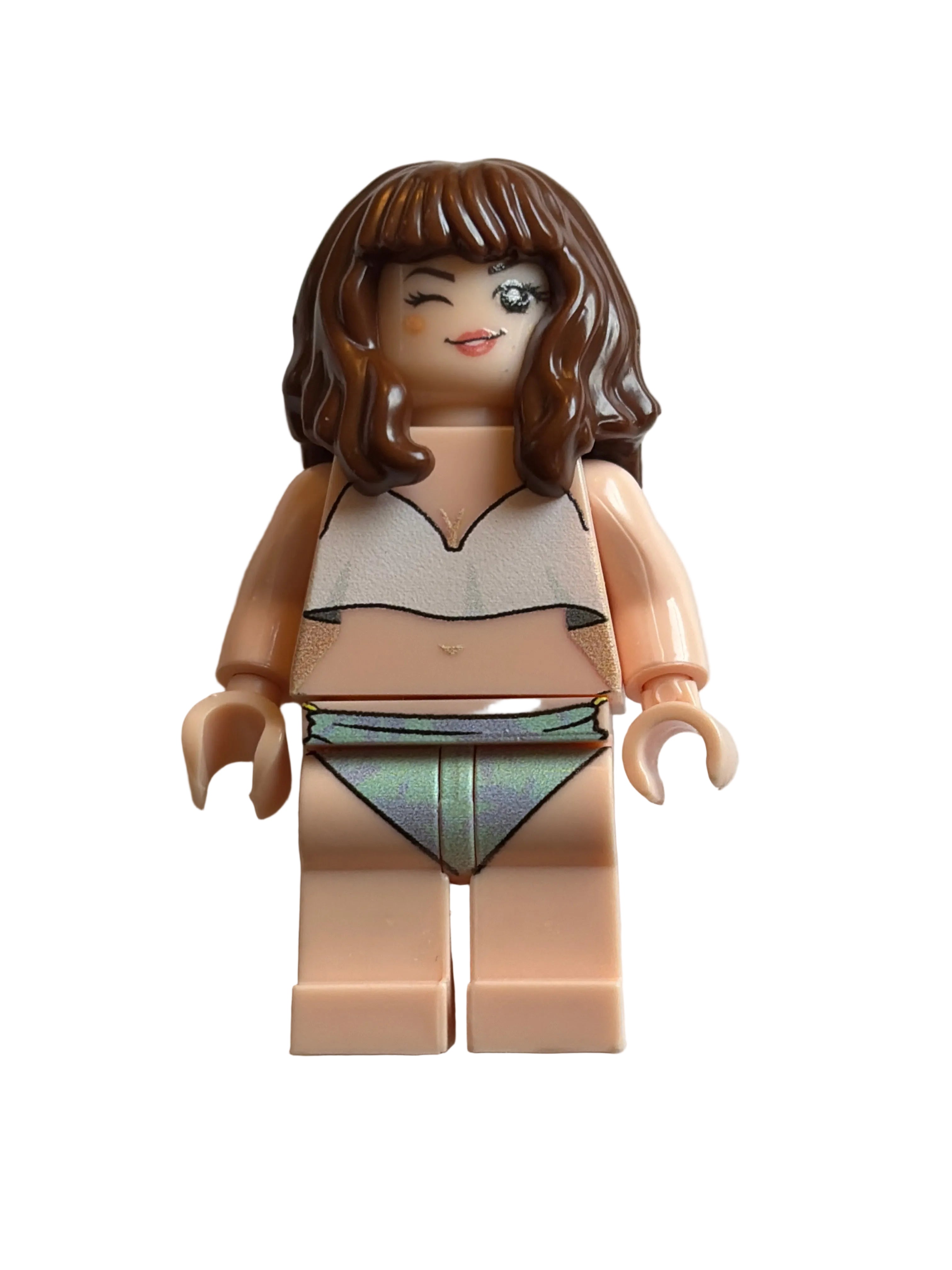 A custom LEGO minifigure torso with brown hair, a beige face and limbs, wearing a white top and a green-gray triangle skirt, lying on a light beige background.