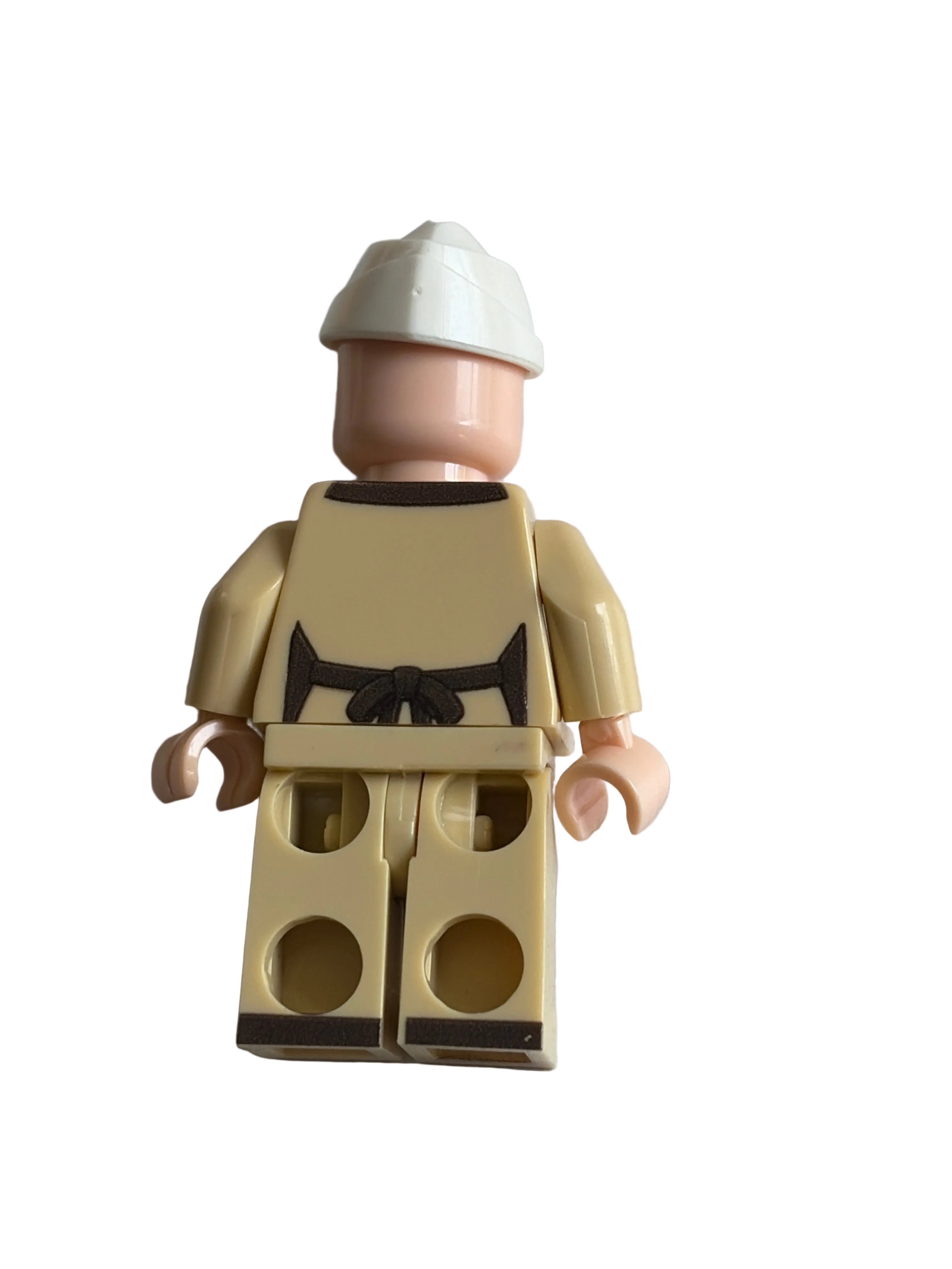 Rear of a minifigire of the iconic tv ad character from Dunkin Donut as a parody Brickin Donuts with a white wedge hat, peach skin-tone arms and legs, and a beige outfit and brown apron, photographed on a plain white background.