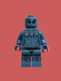 A custom blue female minifigure with a muscular chest, three printed breasts, and black underwear, set against a solid coral-red background.