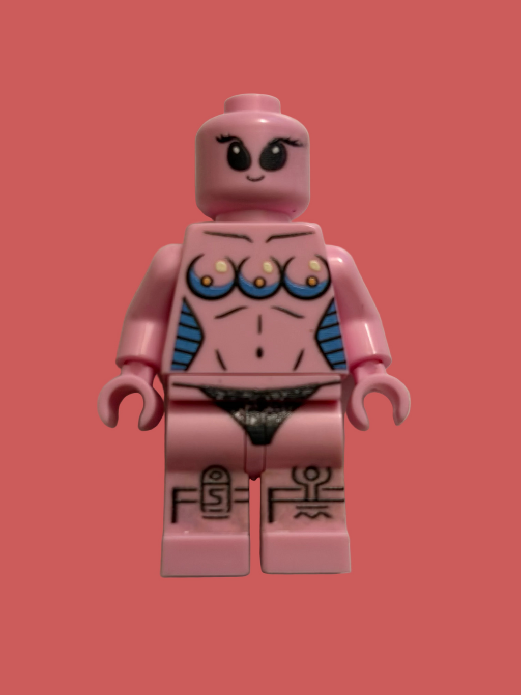 A custom pink toy minifigure with a female face, printed chest details, blue side accents, and black markings on the legs, photographed against a plain off-white background.