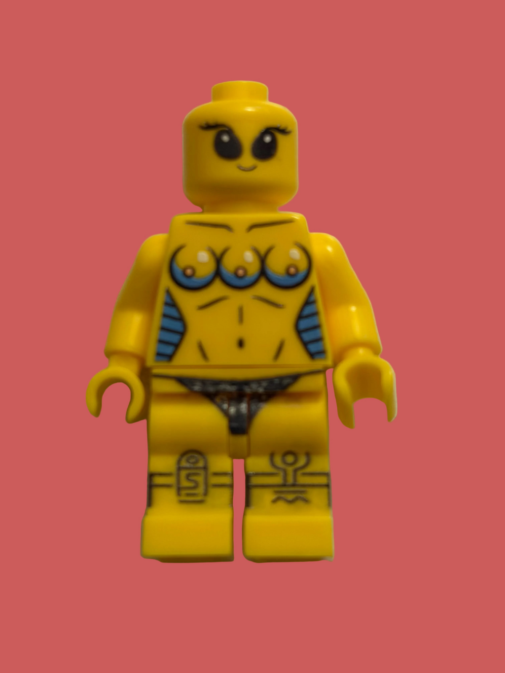 A yellow LEGO style minifigure with custom printed graphics, including three eyes on the chest, blue side accents, and black-and-white patterned underwear, standing against a plain off-white background.