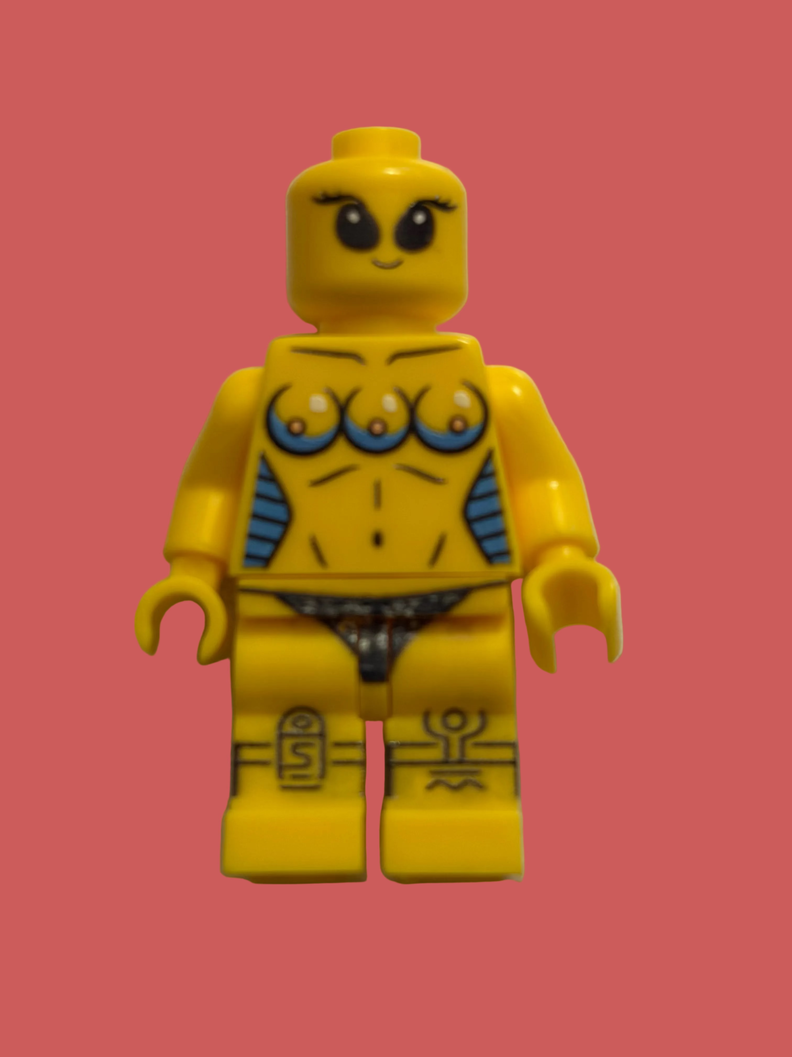 A yellow LEGO style minifigure with custom printed graphics, including three eyes on the chest, blue side accents, and black-and-white patterned underwear, standing against a plain off-white background.