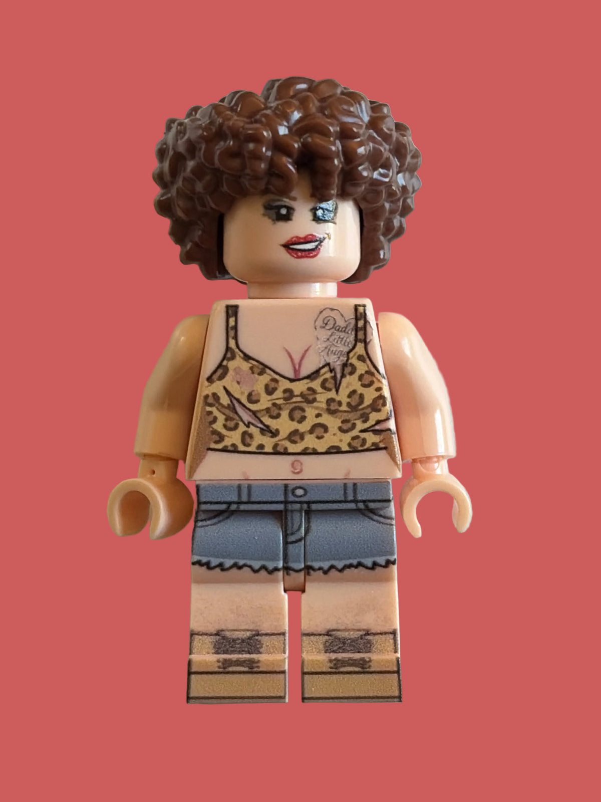 Custom Minifigure with peach skin, leopard print tank top, cutoff Blue Jean legs, brown boots, tattoo, on a light pink background 