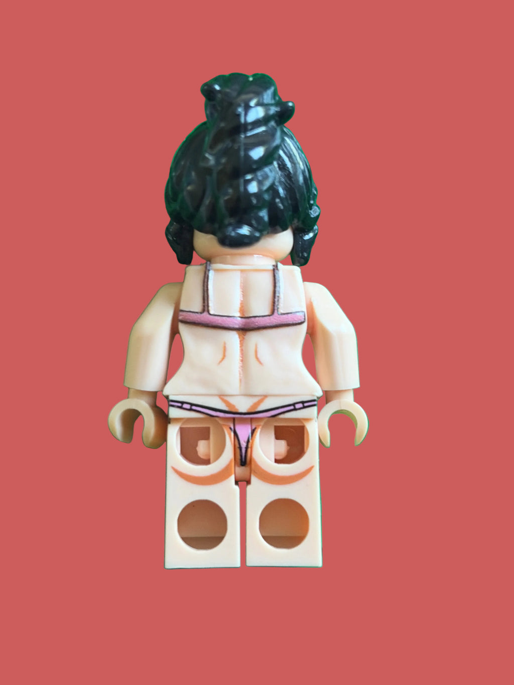 A toy minifigure shown from the back, wearing a beige bikini with purple trim, standing on a bright green stud base.