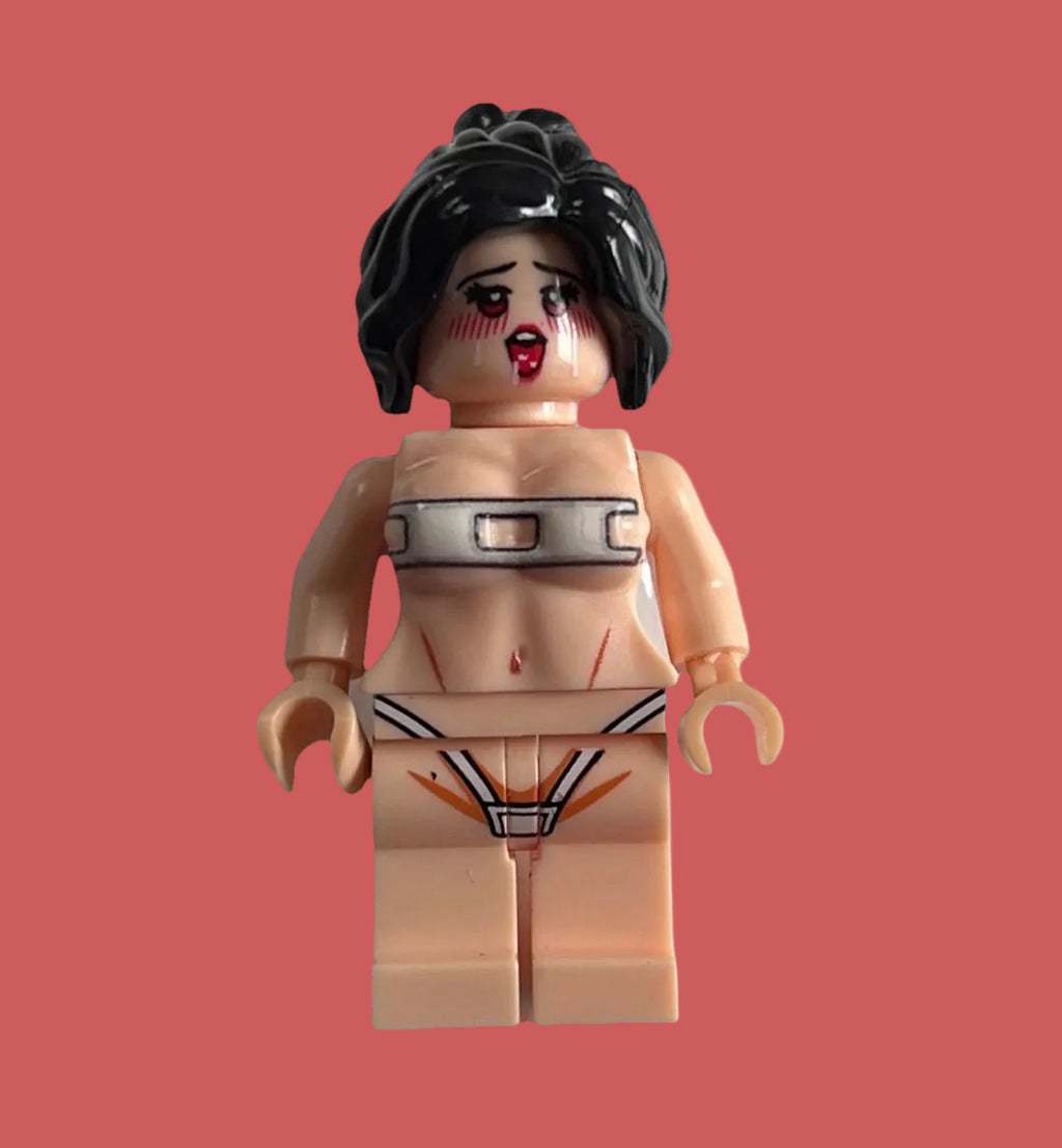 A custom-built female minifigure with black hair, a distressed face, and a beige body, wearing a silver metal collar and a black and white thong with red details, isolated on a pink background.